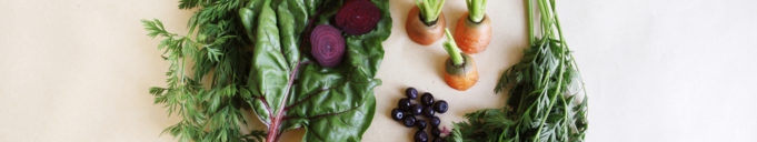 Biojätteitä, kuten salaattia ja punajuurten sekä porkkanoiden naatteja, keittiönpöydällä.