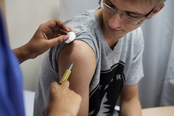 Hoitaja pistää rokotetta asiakkaan käsivarteen.