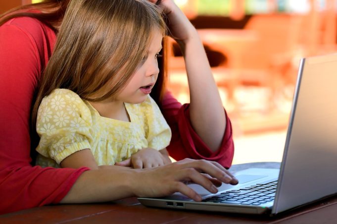 Lapsi käyttää tietokonetta turvallisesti aikuisen kanssa.