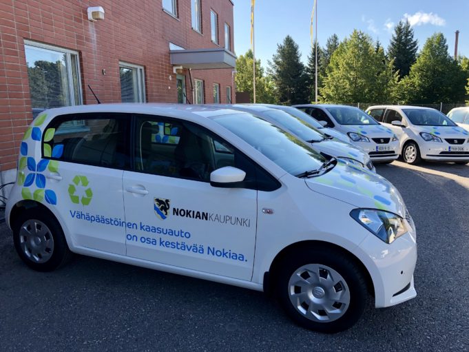 Useita valkoisia Seat Mii -kaasuautoja vierekkäin Nokian kaupungin varikolla. Autoissa on kaupungin teippaukset.