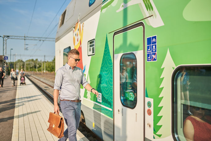 Mies nousee vihreä-valkoisen Intercity-junan kyytiin Nokian asemalaiturilla. Laiturilla on myös muita matkustajia lastenrattaineen.