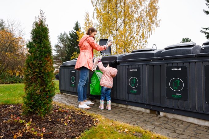 Äiti ja tyttö lajittelevat jätteitä rivissä oleviin syväkeräysastioihin.