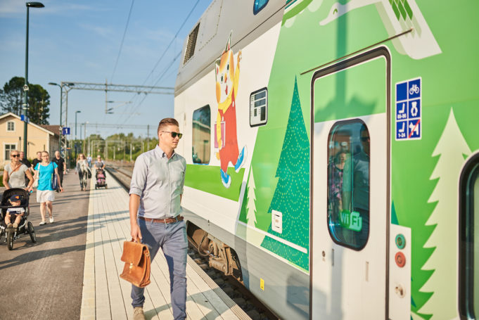 Mies nousee vihreä-valkoisen Intercity-junan kyytiin Nokian asemalaiturilla. Laiturilla on myös muita matkustajia lastenrattaineen.