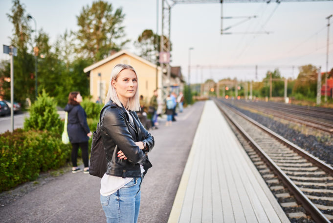 Nuori nainen seisoo Nokian rautatieaseman laiturilla ja odottaa junaa.