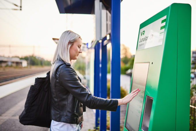 Nuori nainen ostaa junalippua VR:n automaatista Nokian rautatieasemalla.