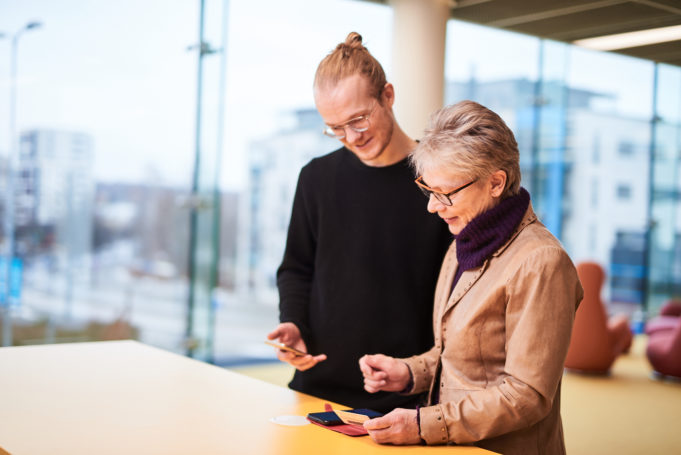 Informaatikko esittelee asiakkaalle henkilökohtaisesti mobiilikirjastosovellusta.