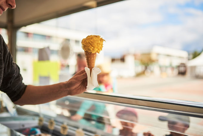 Nuori myyjä ojentaa keltaista jäätelötötteröä kahdelle pienelle pojalle Pirkkalaistorin jäätelökioskilla.