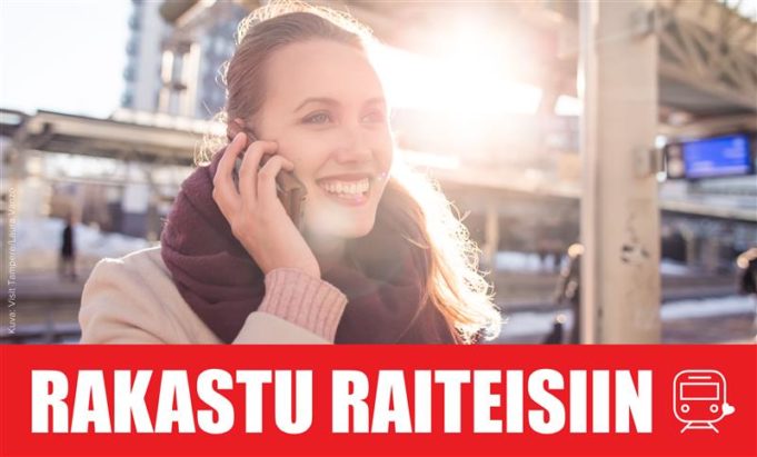 Nainen puhuu matkapuhelimeen rautatieasemalla. Kuvan alla Rakastu raiteisiin -kampanjan tunnus, jossa Rakastu raiteisiin -teksti ja veturin kuva.