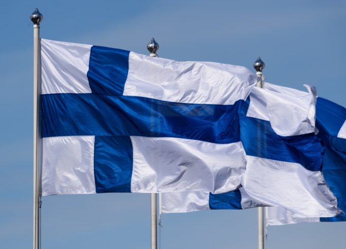 Kolme Suomen lippua liehuu tuulessa