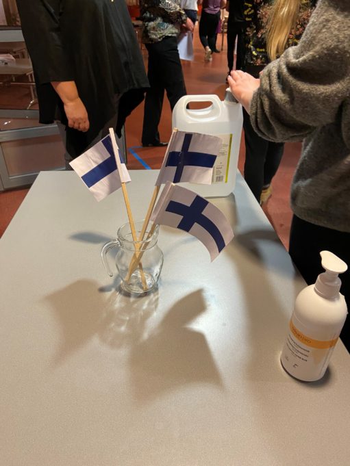 Paperisia Suomen lippuja ja käsidesipulloja pöydällä