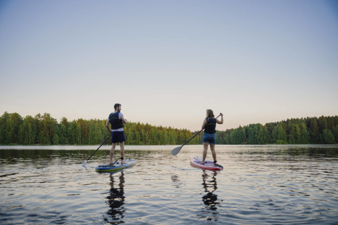 Mies ja nainen sup-lautailevat kesäiltana Pyhäjärvellä.