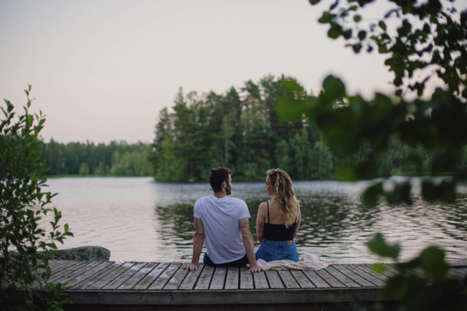 Mies ja nainen istuvat kesäiltana laiturilla Pyhäjärven rannalla Viinikanniemessä.