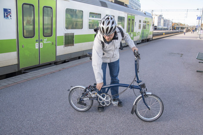 Mies kasaa taittopyörää asemalaiturilla.