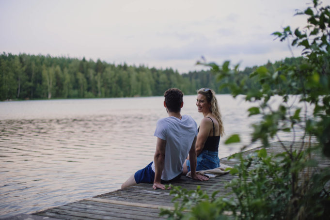 Mies ja nainen istuvat kesäiltana laiturilla Viinikanniemessä Pyhäjärven rannalla.