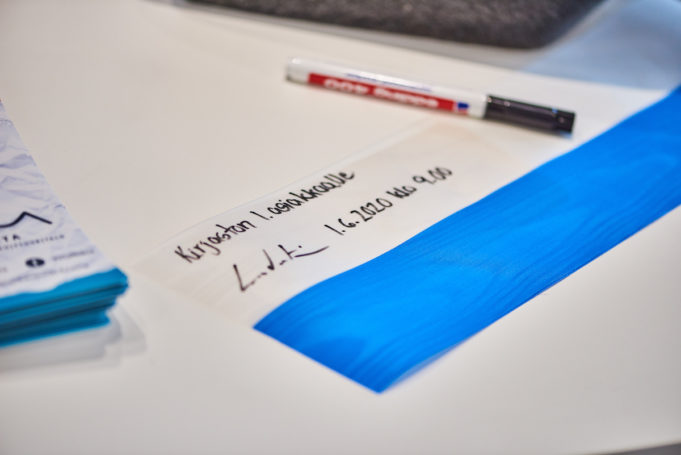Sinivalkoinen airutnauha pöydällä, nauhassa teksti Virran ensimmäiselle asiakkaalle 1.6.2020