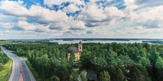 Nokian kirkko sijaitsee korkealla mäellä Nokiavaltatien vieressä ja puiden keskellä.