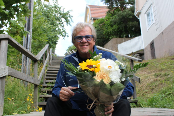 Mikko Alatalo istuu portailla kädessään kukkakimppu ja lasinen Iskelmä Finlandia - palkinto.