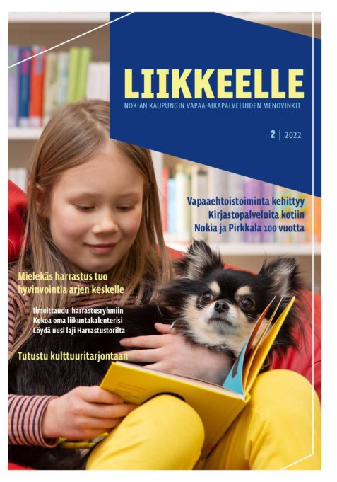 Vapaa-aikapalveluiden ohjelmalehden kansikuvassa lapsi istuu koira sylissään kirjaa lukien.