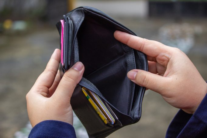 Ihminen pitää käsissään mustaa, nahkaista lompakkoa, jonka seteliosiossa ei ole mitään. Lompakon taskuissa näkyy kortteja.