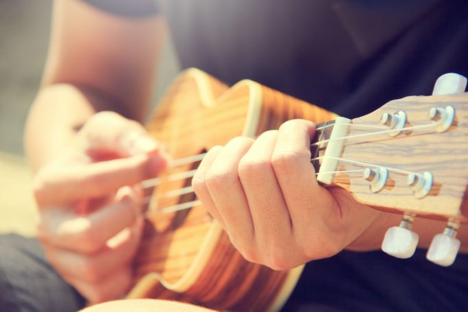 Kuvassa henkilö soittaa neljäkielistä kitaraa tai ukulelea.