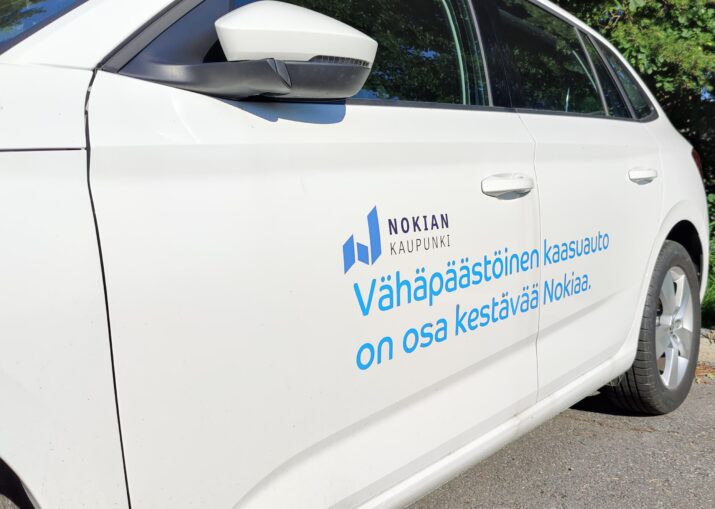Nokian kaupungin biokaasuauto pysäköitynä. Auton kyljessä teippaus: Vähäpäästöinen kaasuauto on osa kestävää Nokiaa.