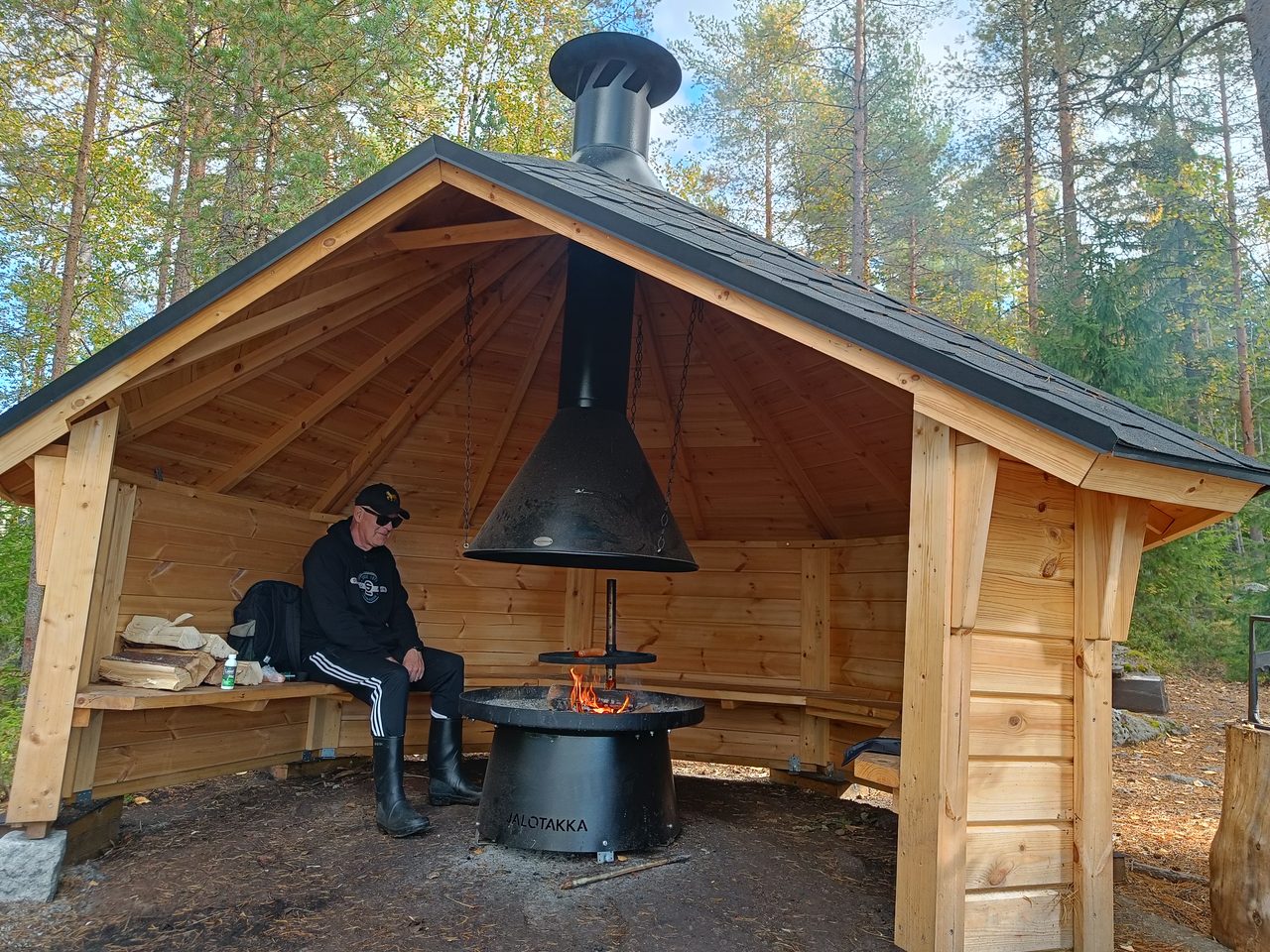 Kuvassa retkeilijä on kotalaavulla paistamassa makkaraa.